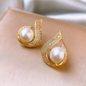 Macro detail of mermaid pearl fish tail earrings with sparkling zircon on silk