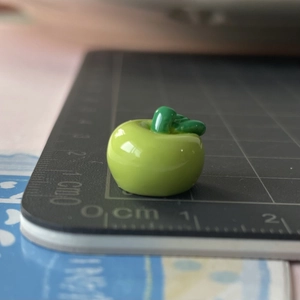 Dettaglio macro di un ciondolo a mela verde in resina 3D per fermagli e gioielli fai da te
