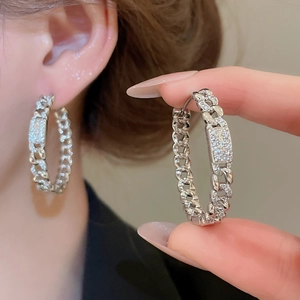 Close-up of 18k gold plated hoop earrings with cubic zirconia and cuban chain design