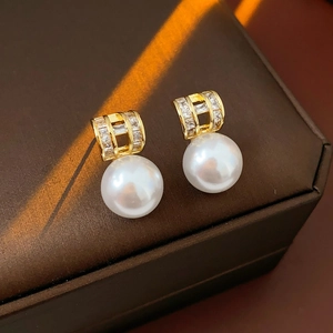 Close-up of gold-plated pearl drop earrings with sparkling crystals on jewelry box