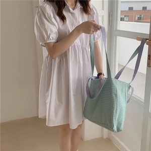 Detalle de bolso tote de lona a cuadros con asas moradas y patrón de cuadrícula azul