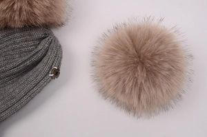 Détail du bonnet en maille avec pompon en fausse fourrure amovible et bouton-pression en métal