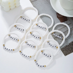 Detail of white polymer clay bead bracelets with gold accents and CHEER letter beads
