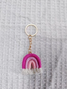 Macro detail of a handmade rainbow knit keychain with pink cotton threads and gold ring