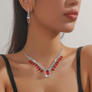 Detailed view of luxury silver necklace and earrings set with red crystals and rhinestones
