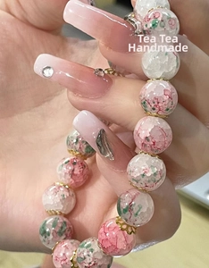 Detailed close-up of pink and green crackle glass beads with gold spacers on a bracelet