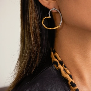 Close-up of heart-shaped two-tone hammer textured earrings on a fashion model