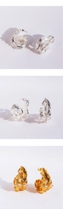 Detailed macro view of silver and gold feather earrings with sparkling cubic zirconia