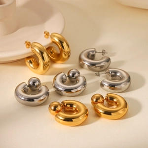 Close-up of polished gold and silver C-shaped chunky earrings in a minimalist style