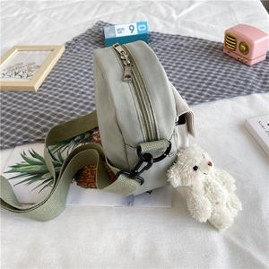 Détail d'un sac bandoulière en toile vert menthe avec un charmant ours en peluche