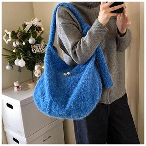 Blue fuzzy plush crossbody bag shown on shoulder in a warm festive indoor setting