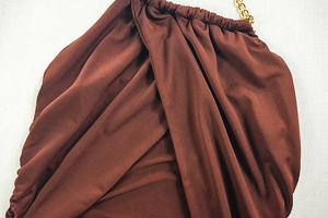 Detail of coffee brown dress showing draped pleated fabric and gold chain straps