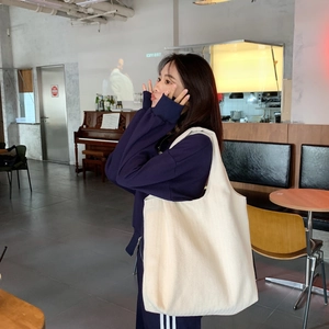 Detail of white canvas tote bag with twill texture and shoulder strap in a cafe
