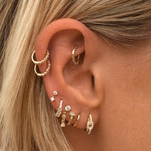 Detail of gold-plated silver earrings set with sparkling zircons on model ear