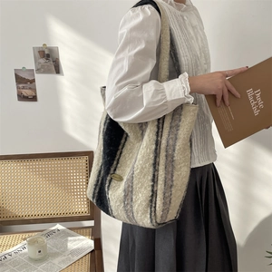 Detail of plush tote bag with black and white stripes worn by a model in a warm room