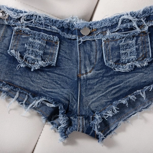 Dettaglio di pantaloncini di jeans blu scuro con bottone metallico e bordi sfrangiati dall'aspetto vissuto