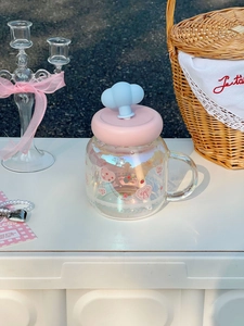 Detail of a cloud glass cup with a pink lid, blue cloud straw cap, and cute floral patterns