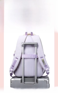 Detail of purple backpack with luggage strap securely attached to suitcase handle