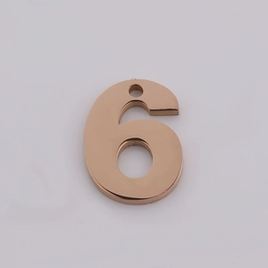 Macro detail of polished rose gold number 6 stainless steel pendant with hanging hole