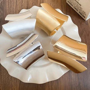 Close-up of matte brushed and polished gold and silver metal bangles on a ceramic plate