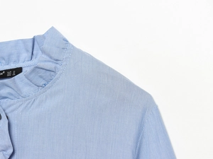 Detail of blue striped poplin shirt with high collar and delicate ruffled trim decoration