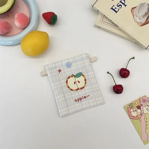 Close-up of cute embroidered apple on a plaid fabric pouch with blue button closure