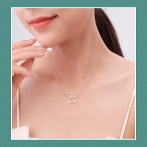S925 silver safety pin necklace with crystal-studded moon and star charms worn by model