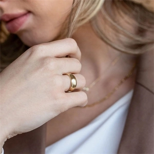 Gros plan d'une bague dôme dorée minimaliste avec une finition miroir hautement polie