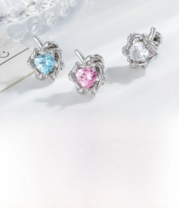 Detailed view of silver cartilage studs with heart-shaped zircon in pink and blue