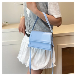Detail view of light blue structured crossbody bag with adjustable strap and top handle