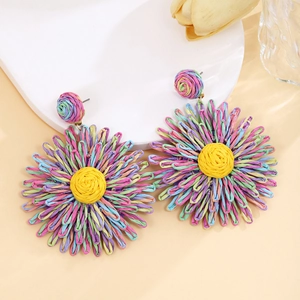 Detailed view of colorful woven raffia flower earrings in a vibrant bohemian style