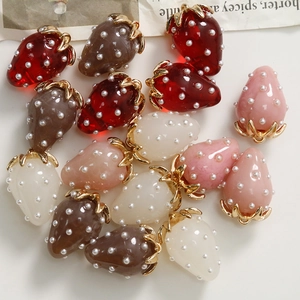 Detailed macro view of strawberry resin charms with white pearls and gold metal hooks