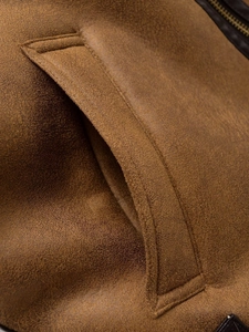 Detail of faux suede pocket on fleece vest showing fine stitching and metal zipper texture