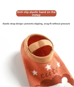 Close-up of cute orange baby floor socks with anti-slip elastic straps and star patterns