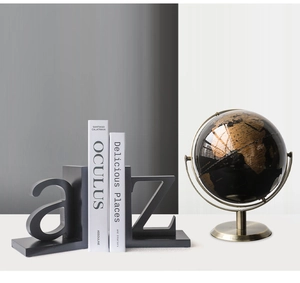 Modern black metal 'a' and 'z' alphabet bookends on a desk with a decorative globe