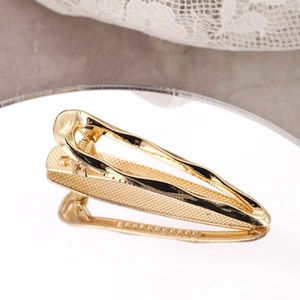 Minimalist golden metal water drop hair clip with polished finish shown on mirror