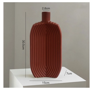 Detail view of red-brown ceramic vase featuring modern vertical pleated ribbed textures
