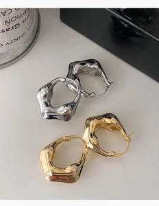 Détail de boucles d'oreilles géométriques avec texture en métal fondu en tons or et argenté