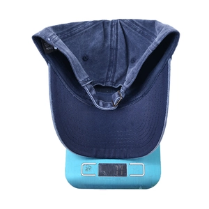 Dettaglio del leggero cappello in cotone lavato blu navy che pesa 77g su una bilancia