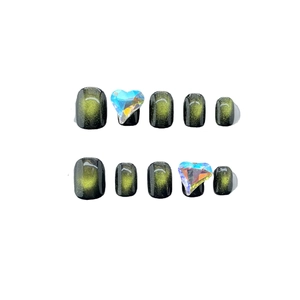 Cat eye press-on nails in green and black with large heart-shaped crystal rhinestones
