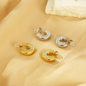 Detail of 18k gold and silver C-shape earrings with zircon inlay on silk background