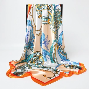 Dettaglio ravvicinato della sciarpa in raso con motivo paisley e stampa floreale oro e arancio