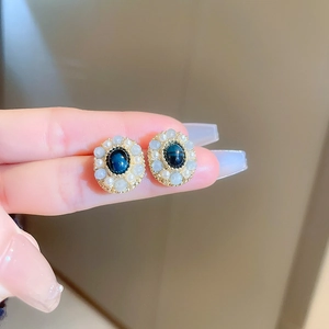 Detail view of a vintage oval blue stone earring surrounded by small white pearls in gold