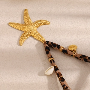 Detail of 18K gold starfish pendant with leopard print strap and tiny seashell accents