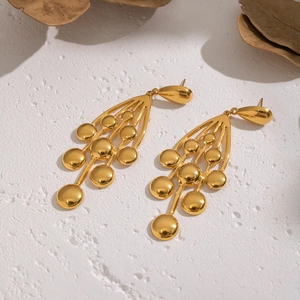 Vue détaillée des boucles d'oreilles grappe de raisin en acier doré sur fond texturé