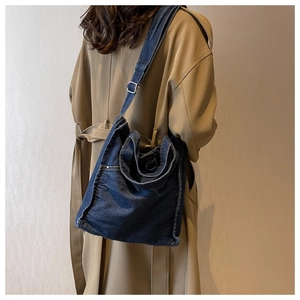 Detail of blue denim tote bag showing fine stitching and adjustable strap on a model