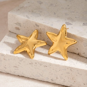 Close-up of golden starfish earrings on light terrazzo stone with natural lighting