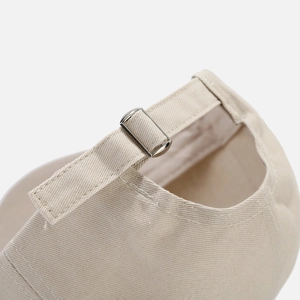 Detail of beige canvas baseball cap featuring an adjustable strap and silver metal buckle