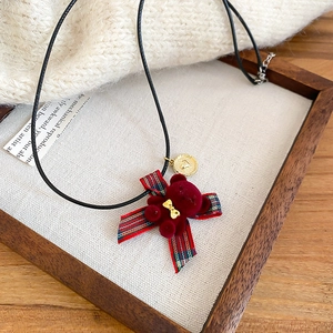 Dettaglio della collana orsetto bordeaux con fiocco dorato e nastro a quadri rosso