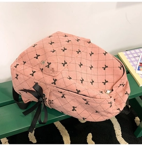 Pink corduroy backpack with diamond pattern and decorative side ribbon bow details